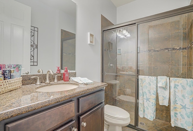 bathroom featuring vanity, toilet, and a shower stall