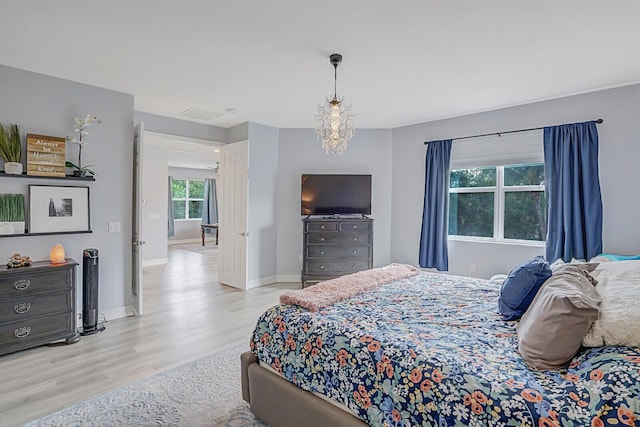 bedroom featuring a notable chandelier, baseboards, and wood finished floors