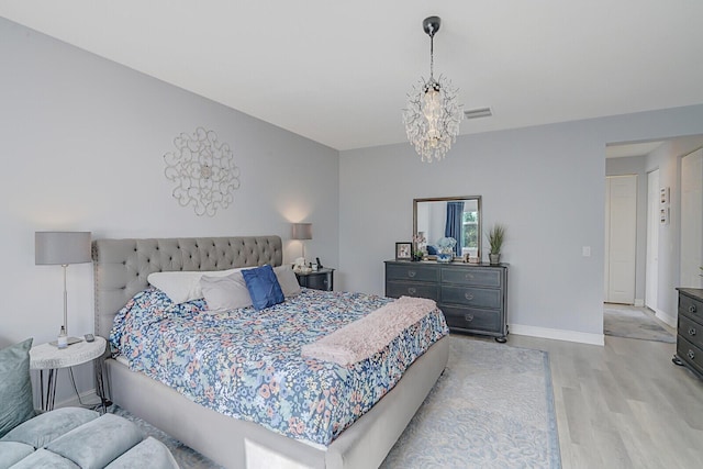 bedroom featuring an inviting chandelier, light wood-style flooring, visible vents, and baseboards