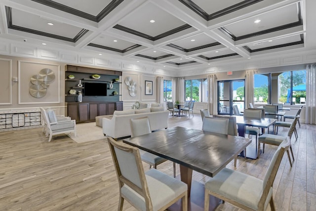 dining area featuring coffered ceiling, beam ceiling, light wood-style flooring, ornamental molding, and a decorative wall