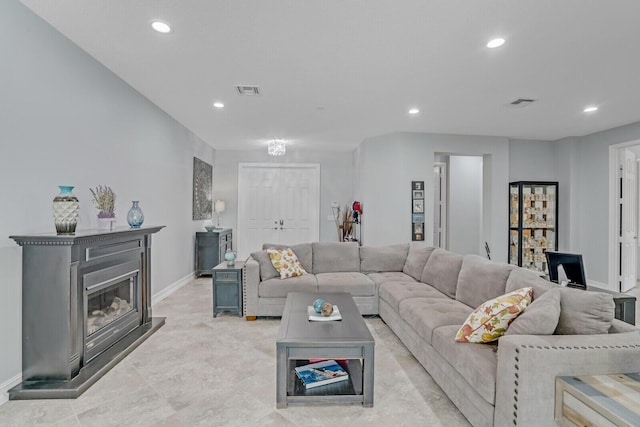 living area featuring a glass covered fireplace, recessed lighting, visible vents, and baseboards