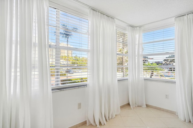 spare room with plenty of natural light, baseboards, light tile patterned floors, and a textured ceiling