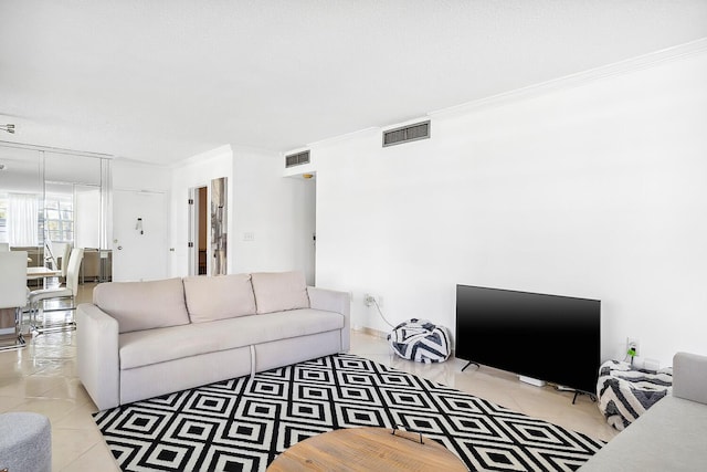 living area featuring visible vents, light tile patterned flooring, and ornamental molding