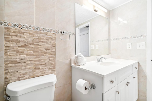 bathroom with vanity, tile walls, and toilet