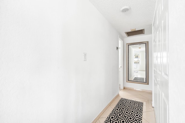 doorway with light tile patterned floors, baseboards, and a textured ceiling