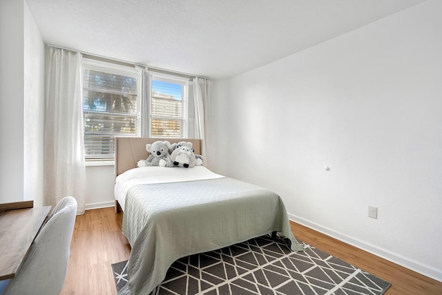 bedroom with baseboards and wood finished floors