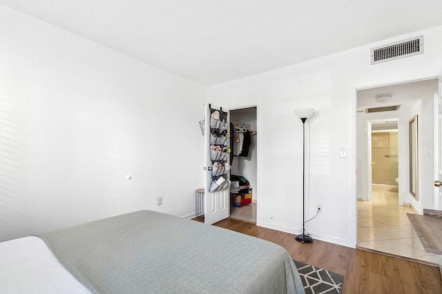 bedroom featuring wood finished floors, visible vents, a closet, and baseboards