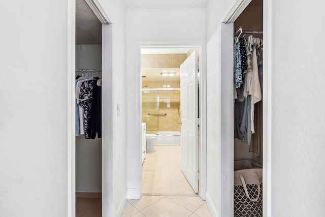 hallway featuring light tile patterned flooring and baseboards