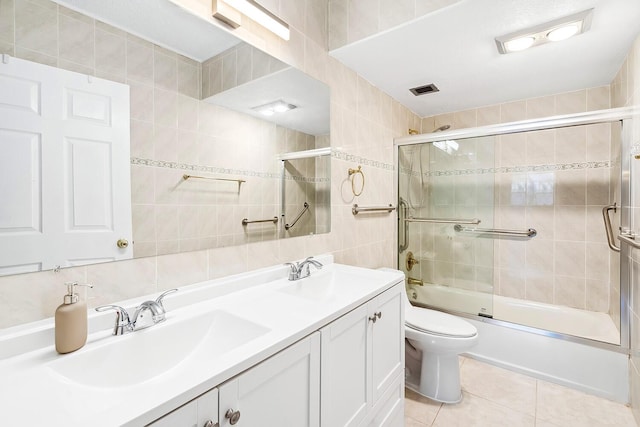 full bathroom with a sink, shower / bath combination with glass door, tile walls, and tile patterned floors