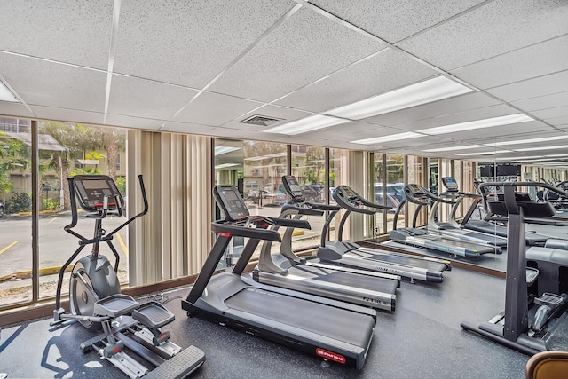 workout area with a drop ceiling, visible vents, and expansive windows