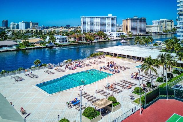 community pool with a city view, fence, a patio area, and a water view