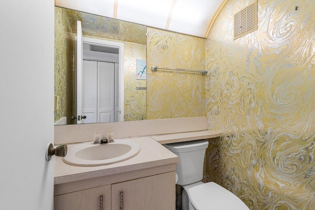 bathroom with visible vents, a closet, vanity, and toilet