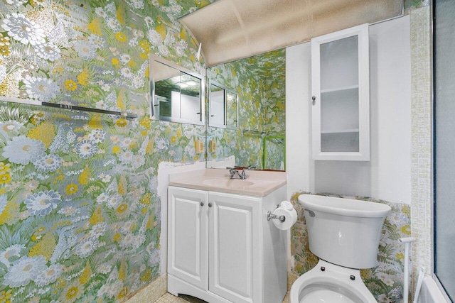 bathroom with toilet, wallpapered walls, and vanity