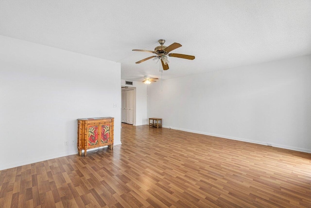 unfurnished living room featuring visible vents, a ceiling fan, a textured ceiling, wood finished floors, and baseboards