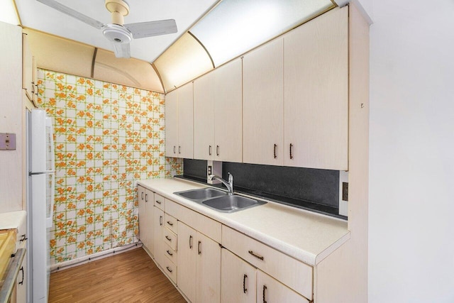 kitchen featuring light countertops, light wood finished floors, a sink, and freestanding refrigerator