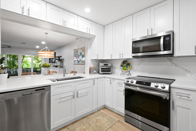 kitchen with stainless steel appliances, a sink, white cabinets, light countertops, and decorative backsplash