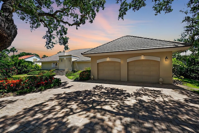 view of front of house featuring a garage, decorative driveway, and stucco siding