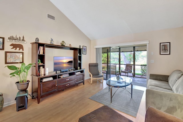 living room with light wood finished floors, visible vents, high vaulted ceiling, and baseboards