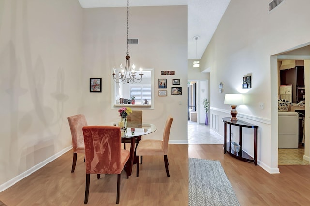 dining room with visible vents, washer / dryer, wood finished floors, and an inviting chandelier