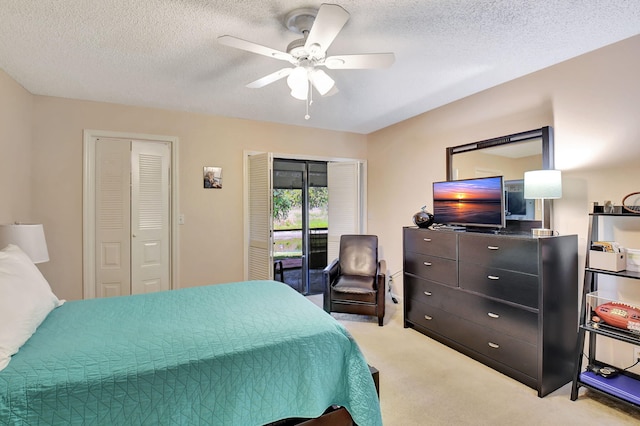 bedroom with a textured ceiling, a ceiling fan, multiple closets, and light carpet