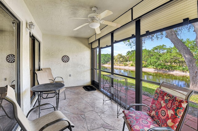 sunroom / solarium with a water view and a ceiling fan