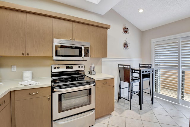 kitchen featuring a textured ceiling, appliances with stainless steel finishes, light brown cabinets, and light countertops