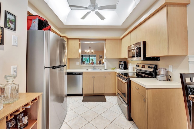 kitchen featuring light brown cabinets, light countertops, appliances with stainless steel finishes, a raised ceiling, and a sink