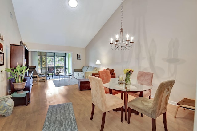 dining area featuring light wood finished floors, visible vents, high vaulted ceiling, and an inviting chandelier