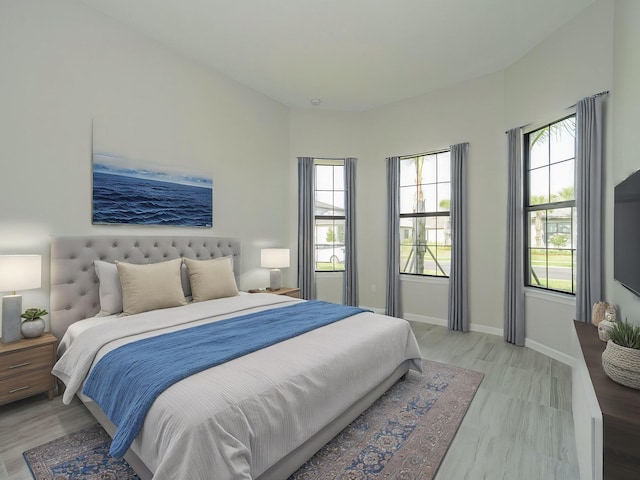 bedroom with light wood-style flooring, multiple windows, and baseboards