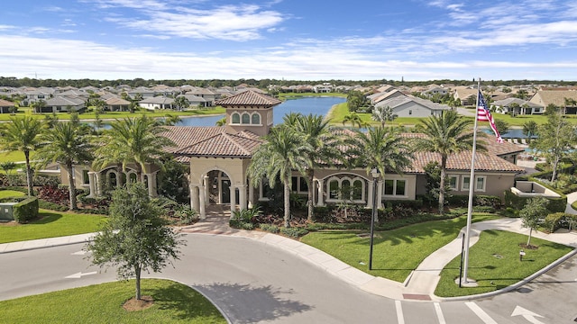 mediterranean / spanish home with a front yard, a tiled roof, a residential view, and stucco siding