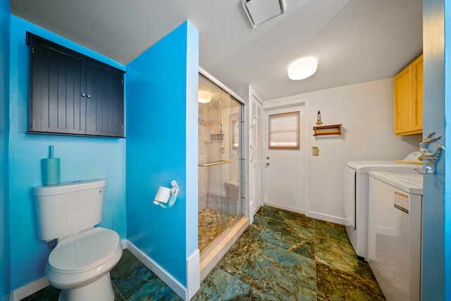 full bath featuring washing machine and clothes dryer, stone finish floor, baseboards, toilet, and a stall shower