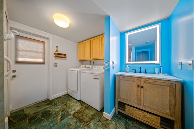 clothes washing area featuring baseboards, washing machine and clothes dryer, cabinet space, and a sink