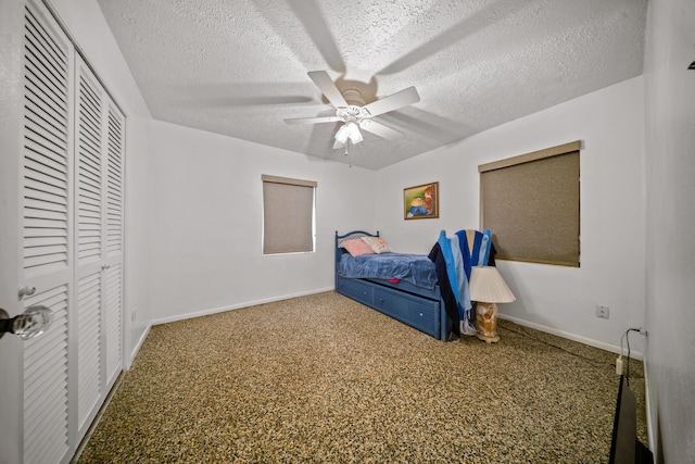 bedroom with baseboards, a textured ceiling, carpet floors, a ceiling fan, and a closet
