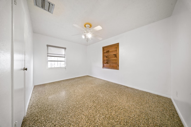 spare room featuring a textured ceiling, visible vents, baseboards, ceiling fan, and speckled floor