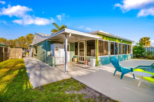 back of house with a yard, a sunroom, fence, and a patio