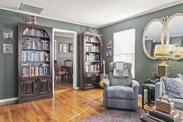 sitting room featuring visible vents, wood finished floors, and ornamental molding