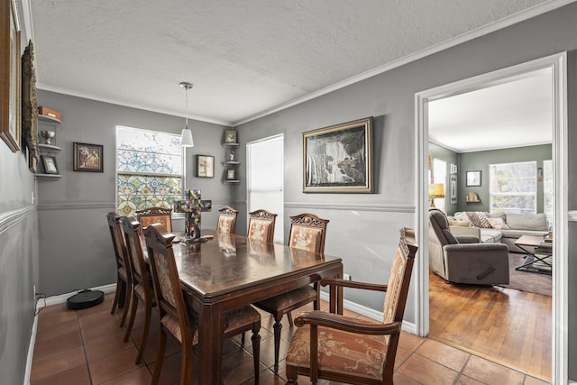 dining room featuring tile patterned floors, baseboards, a textured ceiling, and crown molding