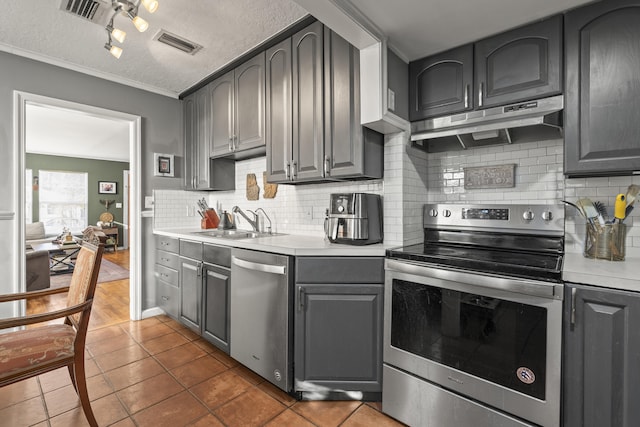 832 Lytle St, West Palm Beach, FL 33405 - kitchen featuring appliances with stainless steel finishes, under cabinet range hood, light countertops, dark tile patterned flooring, and gray cabinets
