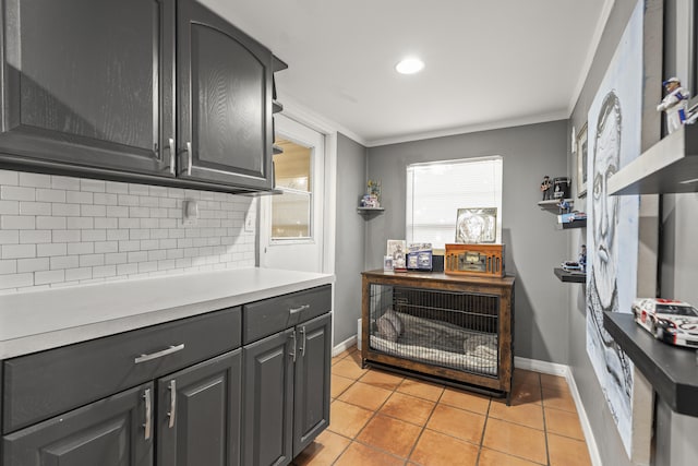 kitchen featuring backsplash, light tile patterned flooring, ornamental molding, and light countertops