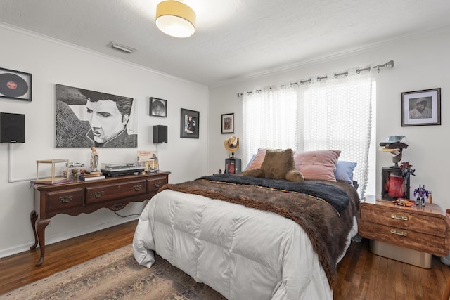 bedroom featuring visible vents, a textured ceiling, wood finished floors, and ornamental molding