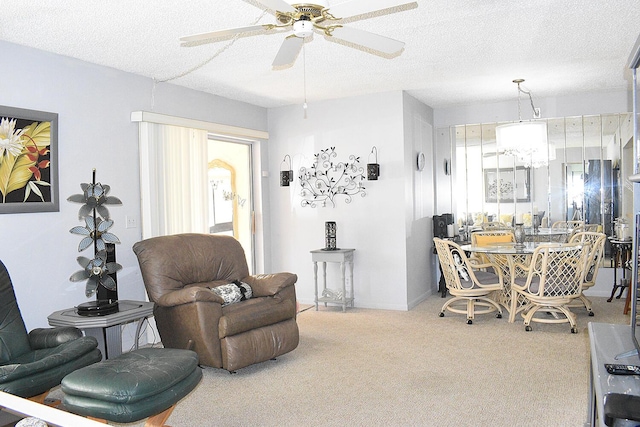 carpeted living room featuring ceiling fan with notable chandelier, baseboards, and a textured ceiling