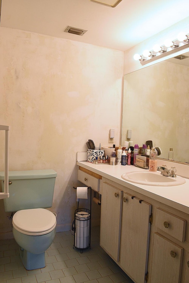 bathroom with vanity, toilet, and visible vents