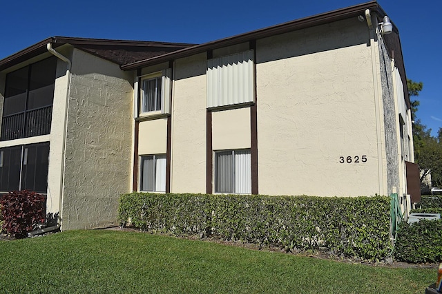 view of side of home with a lawn and stucco siding