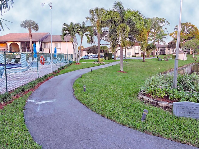 view of community with a pool, a lawn, and fence