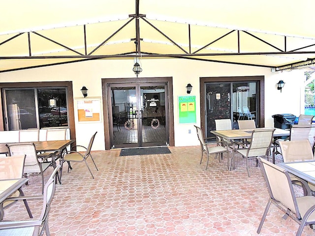 property entrance featuring stucco siding, outdoor dining space, and a patio area