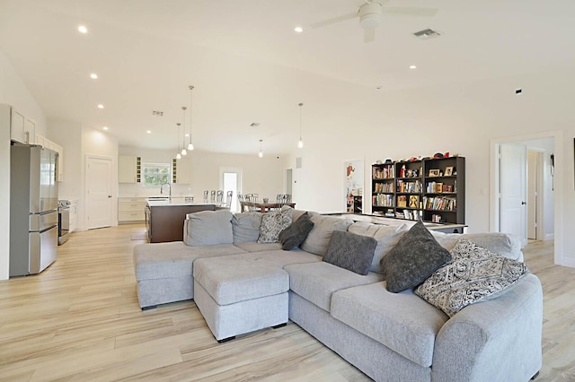 living area with light wood finished floors, visible vents, recessed lighting, and high vaulted ceiling