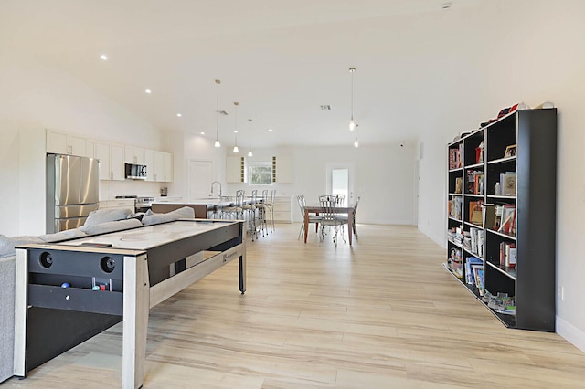 rec room with light wood finished floors, recessed lighting, and high vaulted ceiling