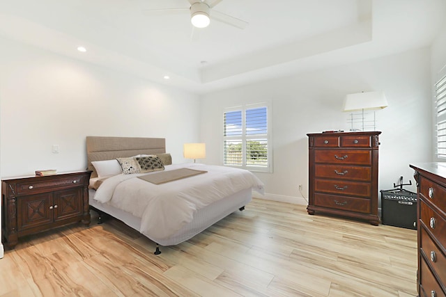 bedroom featuring a raised ceiling, light wood-style flooring, recessed lighting, baseboards, and ceiling fan