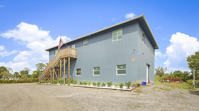 view of side of property featuring stucco siding and stairs