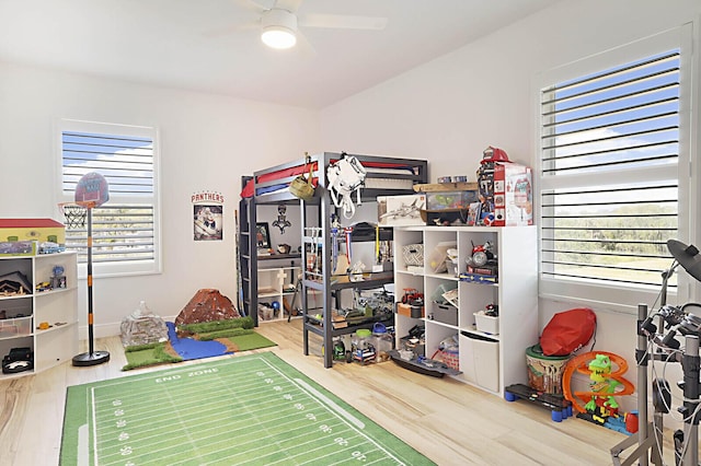 recreation room featuring wood finished floors, a healthy amount of sunlight, and ceiling fan